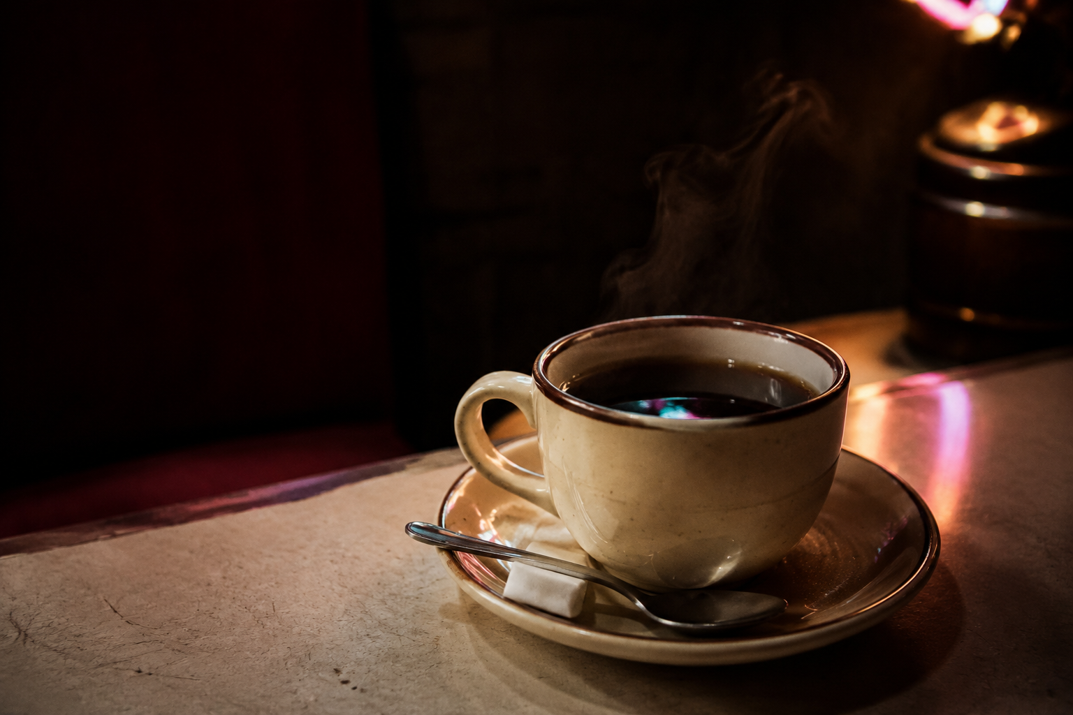 縁に茶色のラインが入った厚手のカップに注がれたブレンドコーヒー。湯気が立ち、受け皿には角砂糖とスプーンが添えられている。